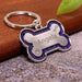 Blessing Sells personalized silver bone-shaped pet ID tag with glittery purple border and paw print engraving.