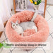 Blessing Sells pink plush pet nest with a grey and white cat curled up inside. Round, cozy, and comfortable.