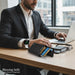 Blessing Sells white smartwatch with a round face displaying time and battery, worn by a man in a suit at a desk.